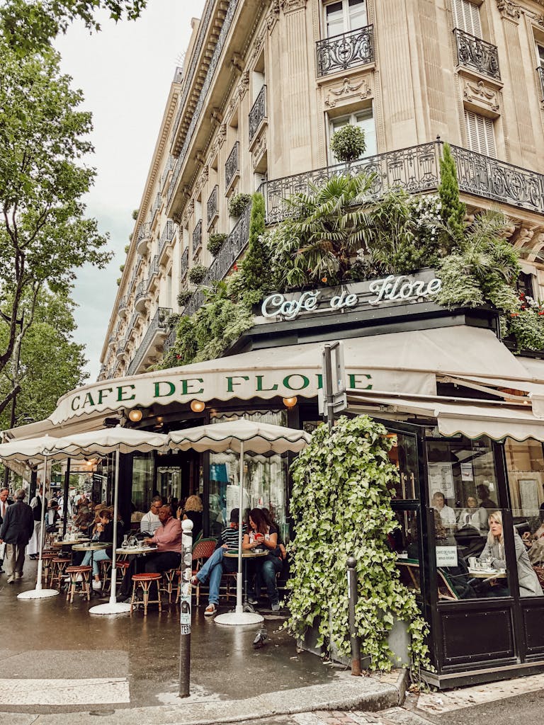 A bustling scene at Cafe de Flore in Paris featuring vibrant greenery and classic architecture.