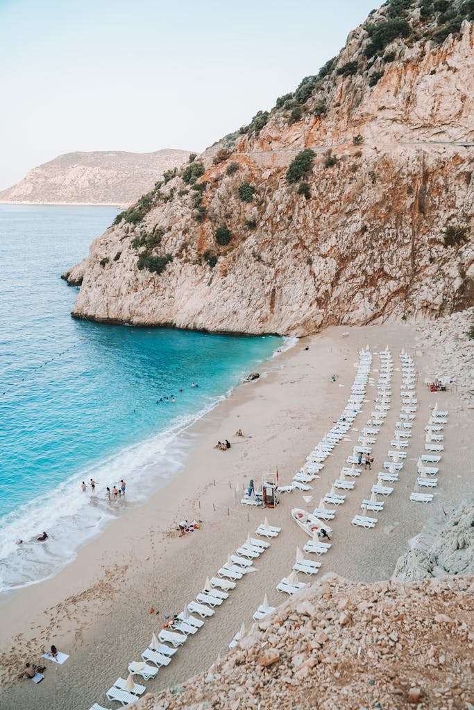 Beautiful beach in Antalya featuring turquoise waters and rows of lounge chairs under rocky cliffs.