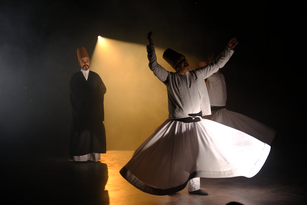 Traditional Sufi dance performed by Whirling Dervishes under dramatic stage lighting.