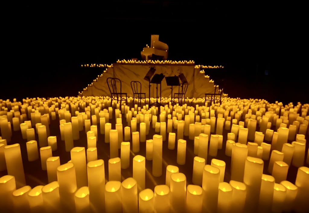 Elegant stage illuminated by candles, featuring piano and music stands, set for a performance.
